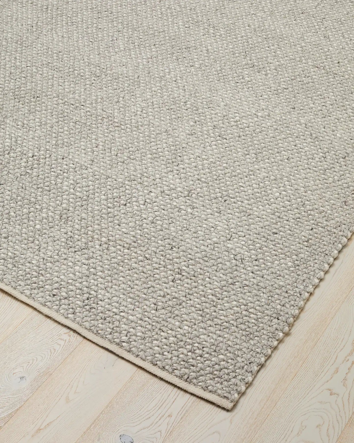 A close-up view of the corner of feather Emerson Rug with a textured design, showcasing its thick weave and clean edges.
