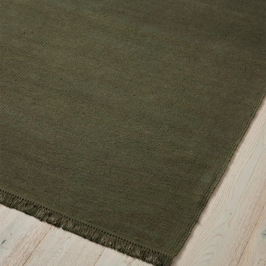 weave emilio kale rug with frayed edge on a wooden floor